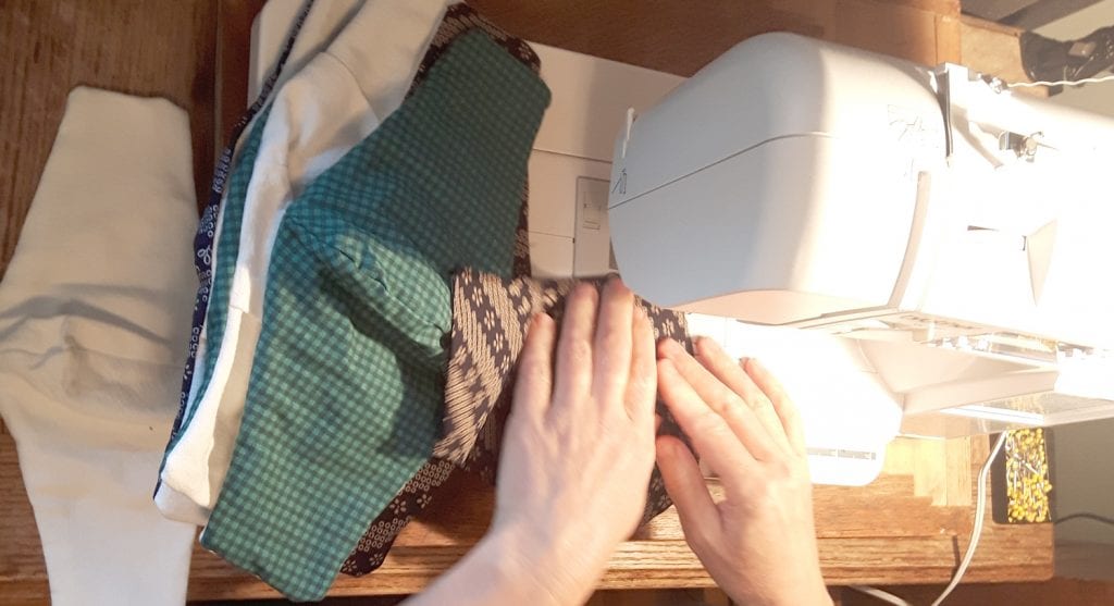 Sewing machine with hands at base and several face masks