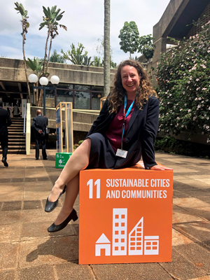 Image of Jennie Moore sitting on the Sustainable Development Goal 11 cube for Sustainable Cities and Communities.