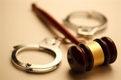 A gavel and a pair of handcuffs on a beige background.