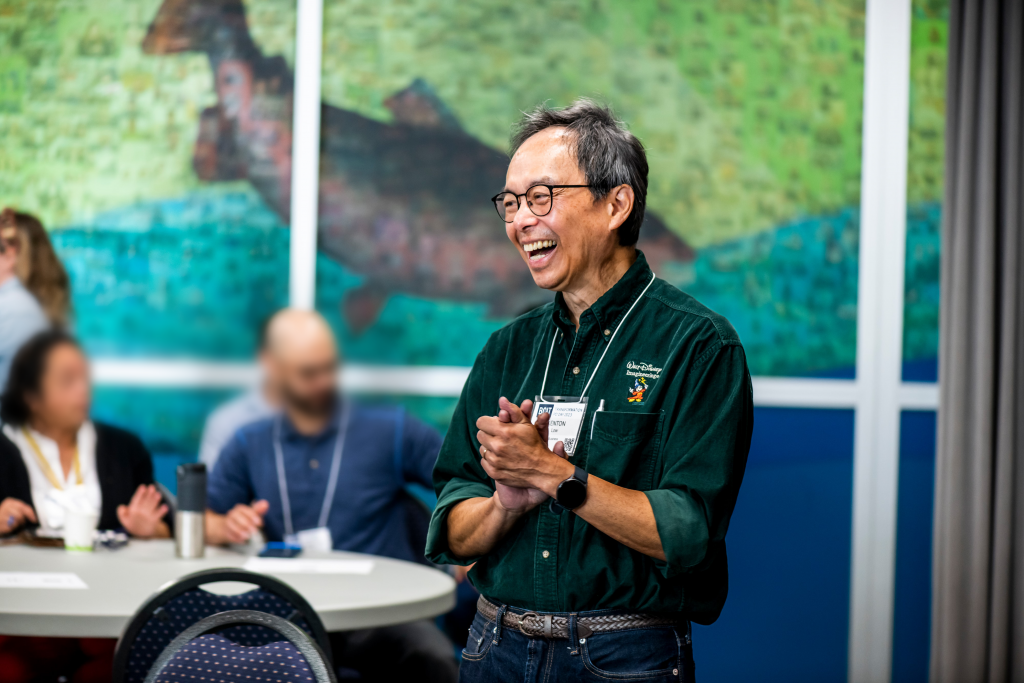 Close-up of smiling man in green Disney shirt presenting to a group