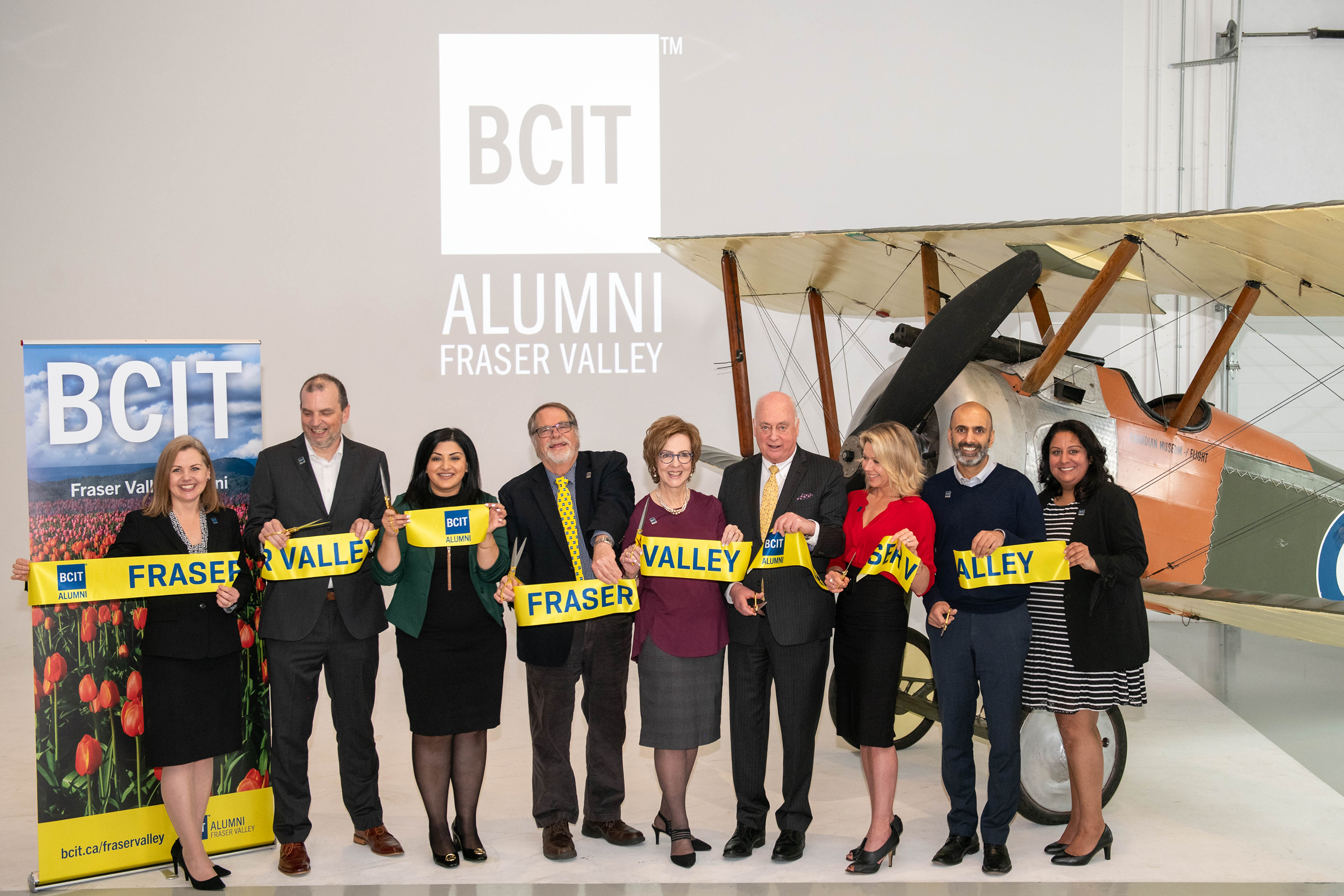 9 representatives from BCIT and Fraser Valley organizations cutting a yellow ribbon