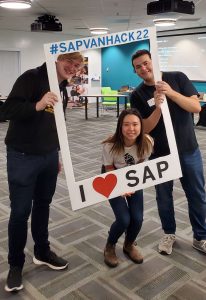 Three students smile while holding a paper I love SAP photo frame