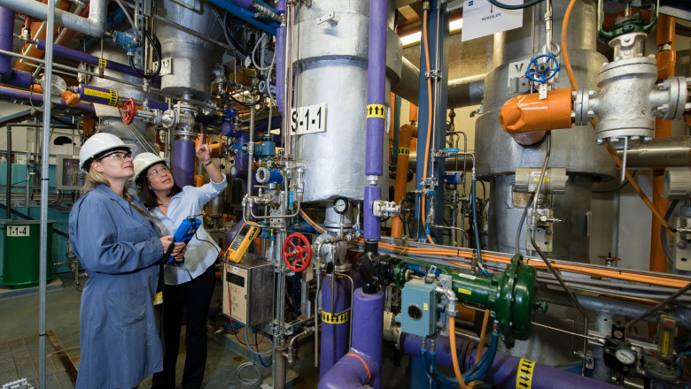 a female student and instructor in a boiler room staring up at the machiner.