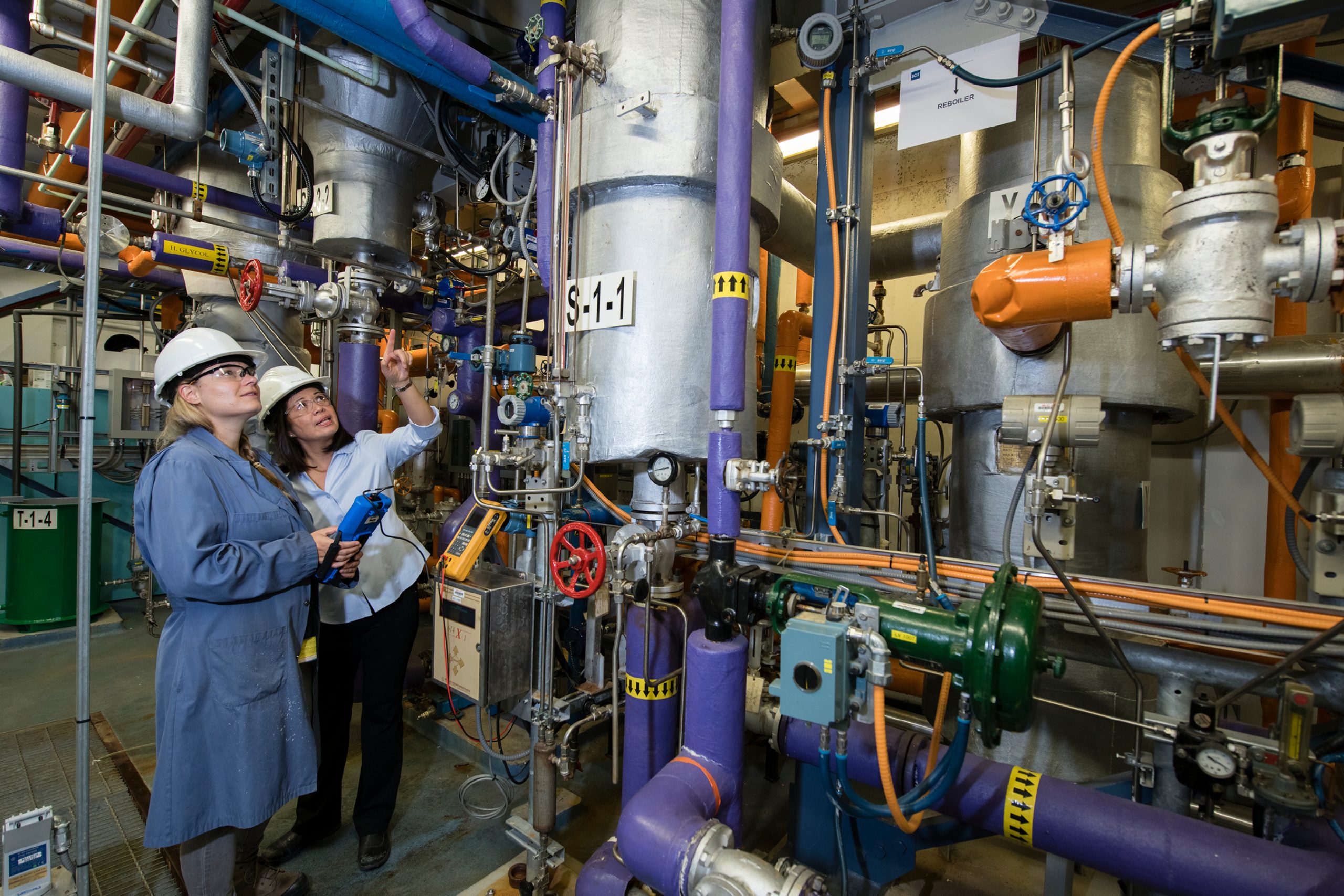 a female student and instructor in a boiler room staring up at the machiner.