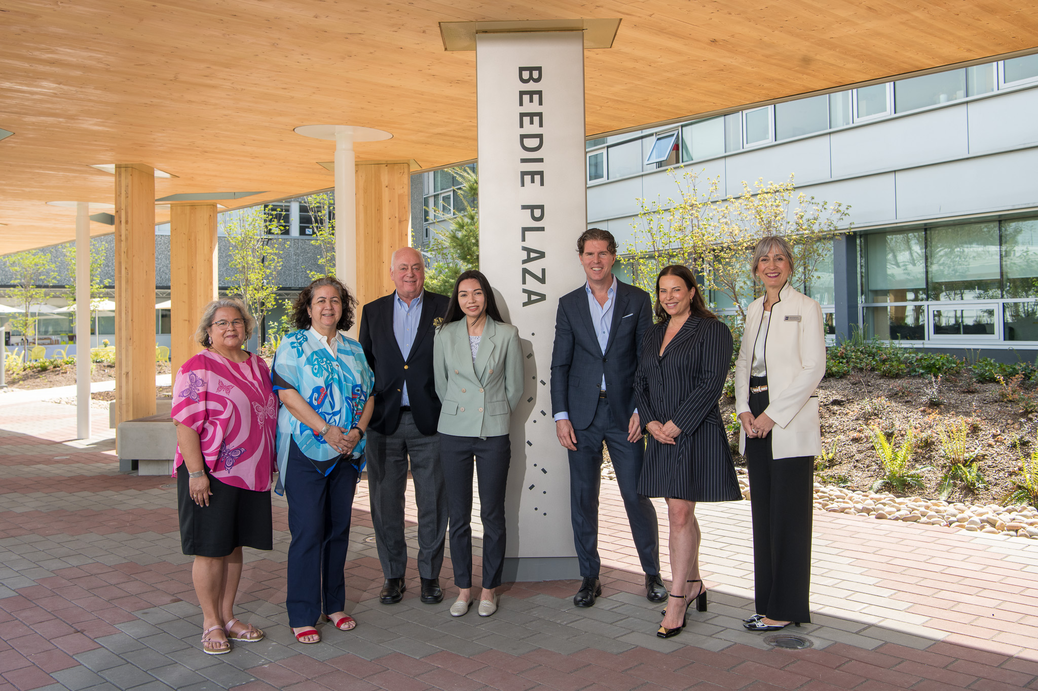 Seven people gather around the Beedie Plaza pillar to celebrate the unveiling of the new Beedie Plaza at the BCIT Burnaby Campus.