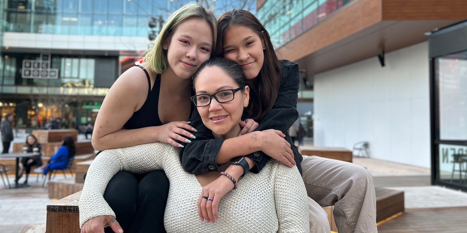 BCIT alumna Susanne Muldon sits between two of her teenage daughters smiling