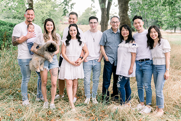 The Hui BCIT Alumni Family poses in jeans and white t-shirts on grass