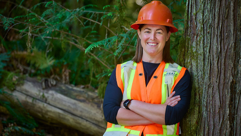 bcit alumna molly hudson poses in hard hat and vest in forest