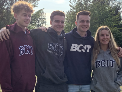 four students, the Waldbauer grandchildren, stand smiling in BCIT sweaters