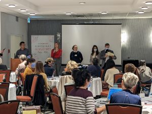 5 people presenting in front of an audience in a conference room