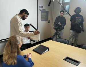 students prepare to film video in a meeting room