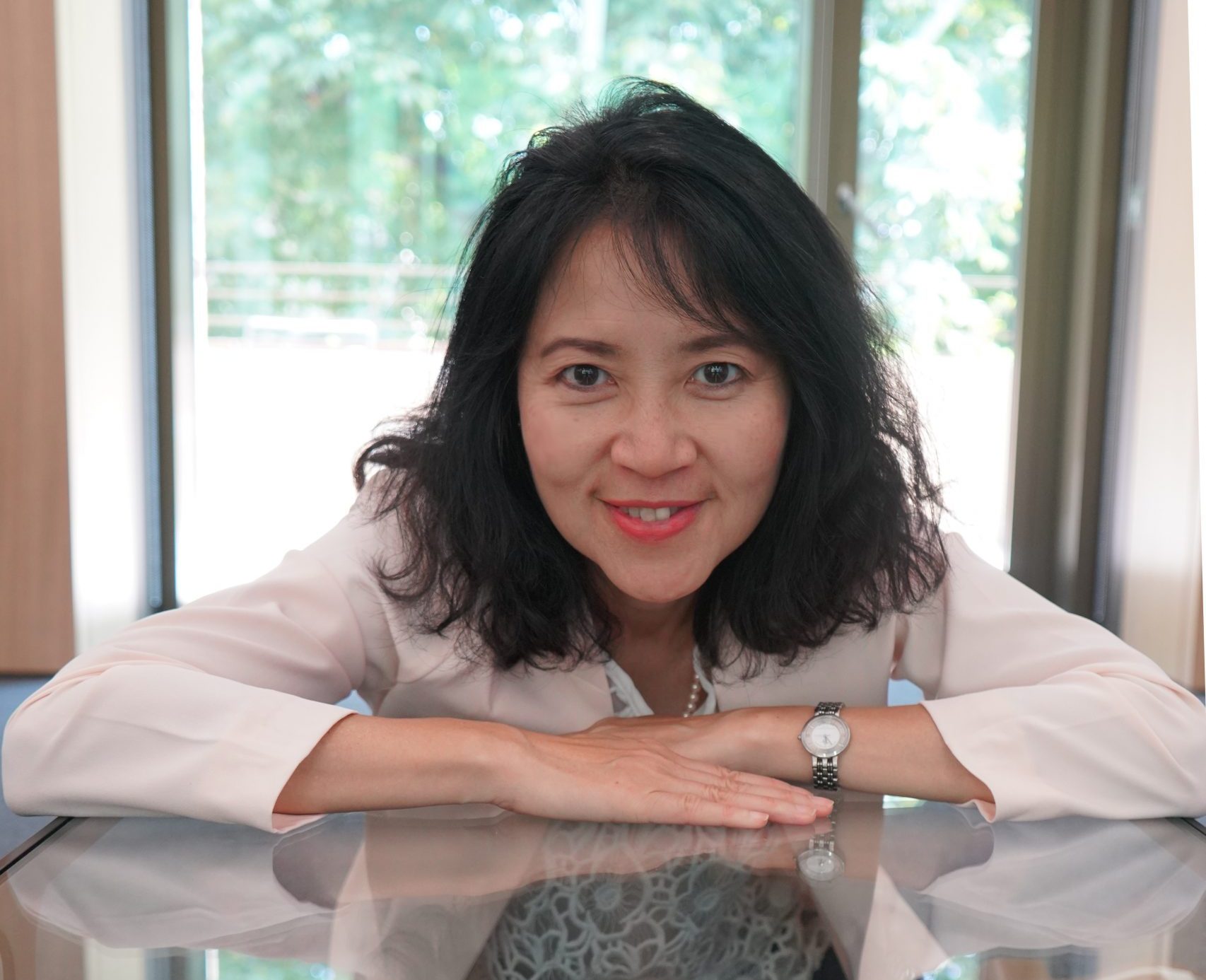 Joanna elaning on a table wit white blouse and a silver watch.