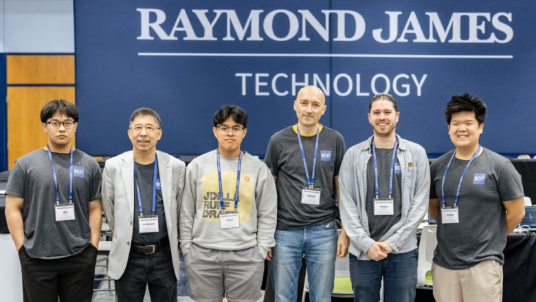 six men of a range of ages and backgrounds stand in front of a banner that reads "Raymond James Technology"