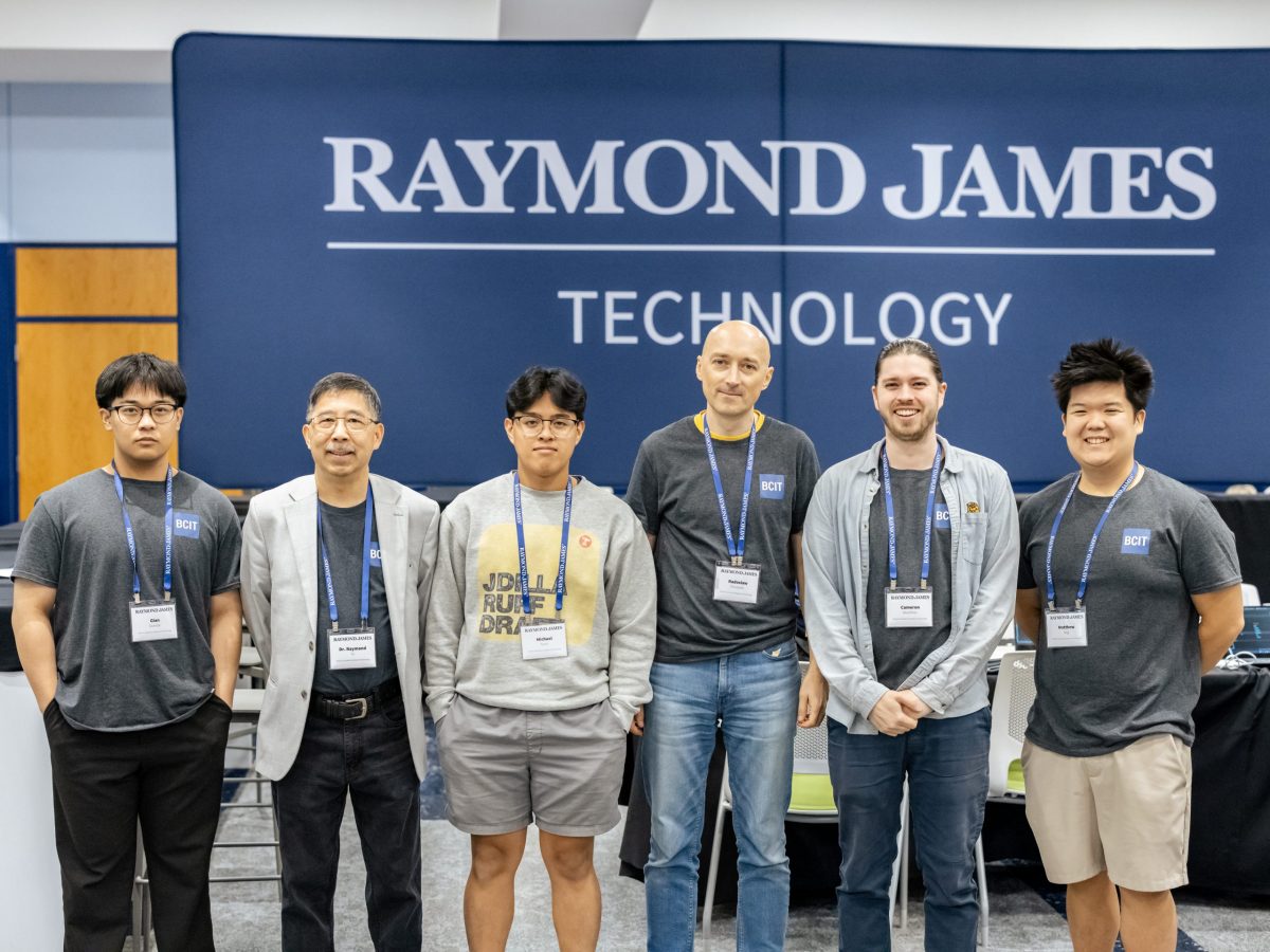 six men of a range of ages and backgrounds stand in front of a banner that reads "Raymond James Technology"