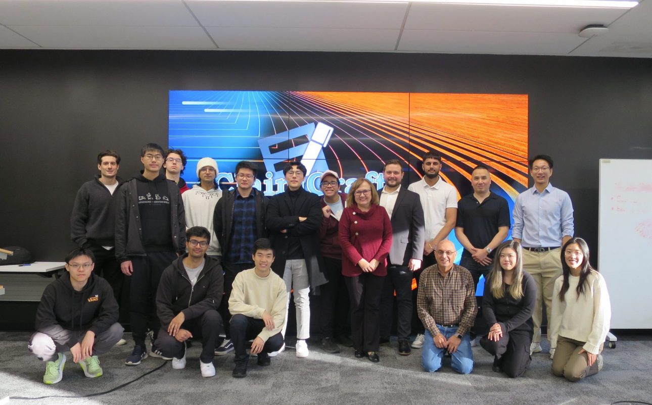 Group of young adult students and two faculty pose for group photo in a meeting room