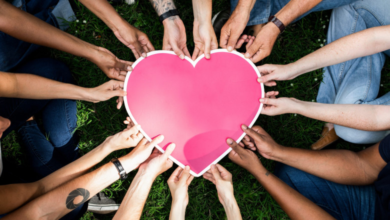 Group of people holding a pink heart icon