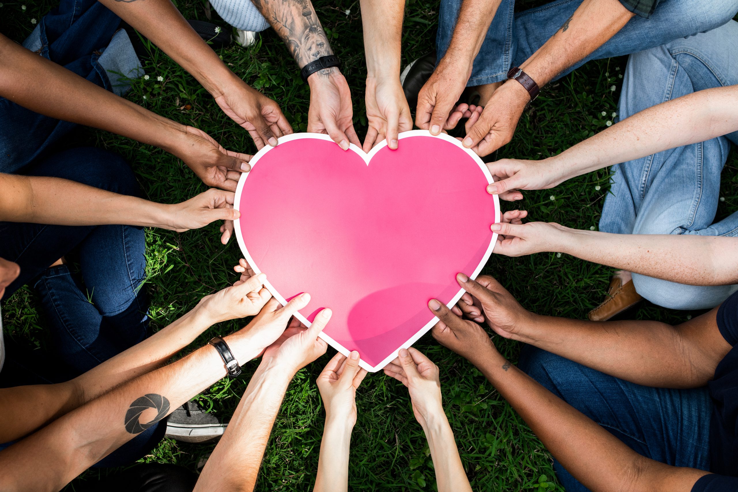 Group of people holding a pink heart icon