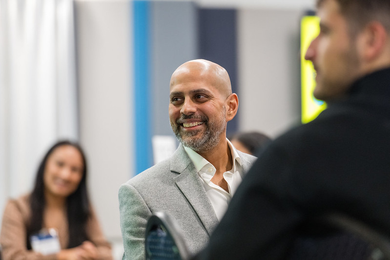 smart-looking man in suit smiles at someone off camera